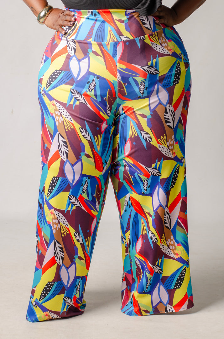 Colorful patterned wide leg pants worn by a plus size model on a plain background