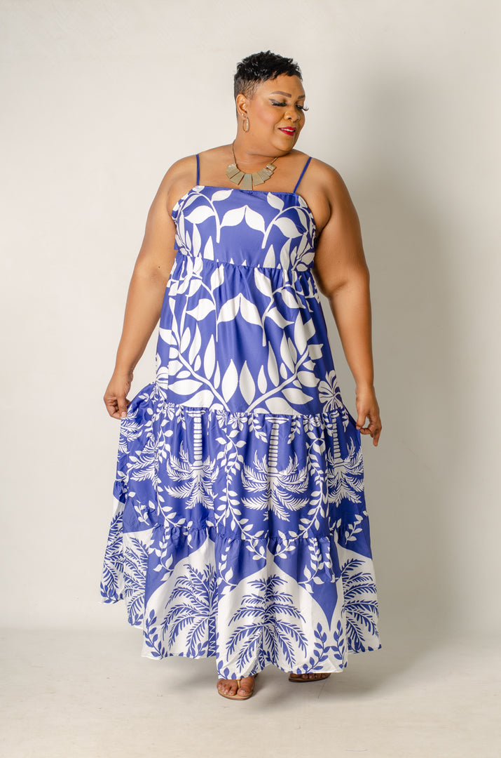 Woman wearing a blue and white floral dress against a plain background